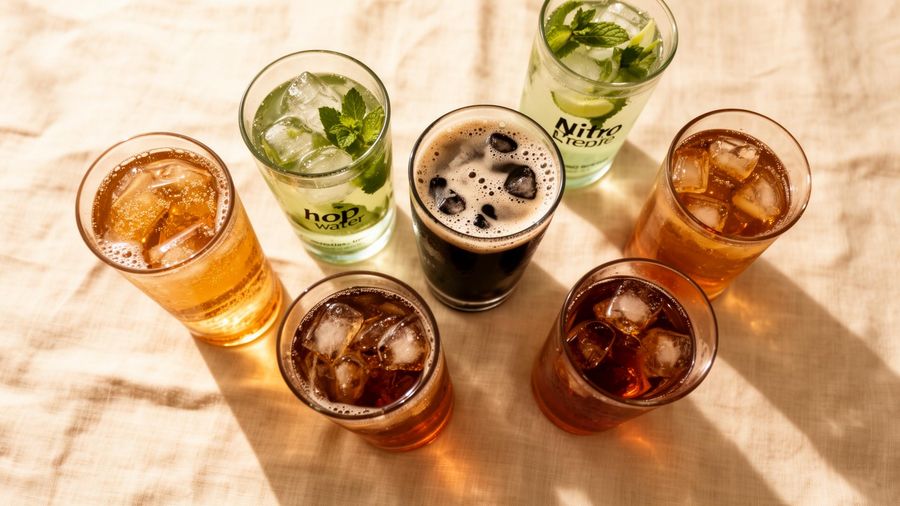 Overhead spread of non-alcoholic draft beverages: sparkling tea, hop water, nitro cold brew, iced tea